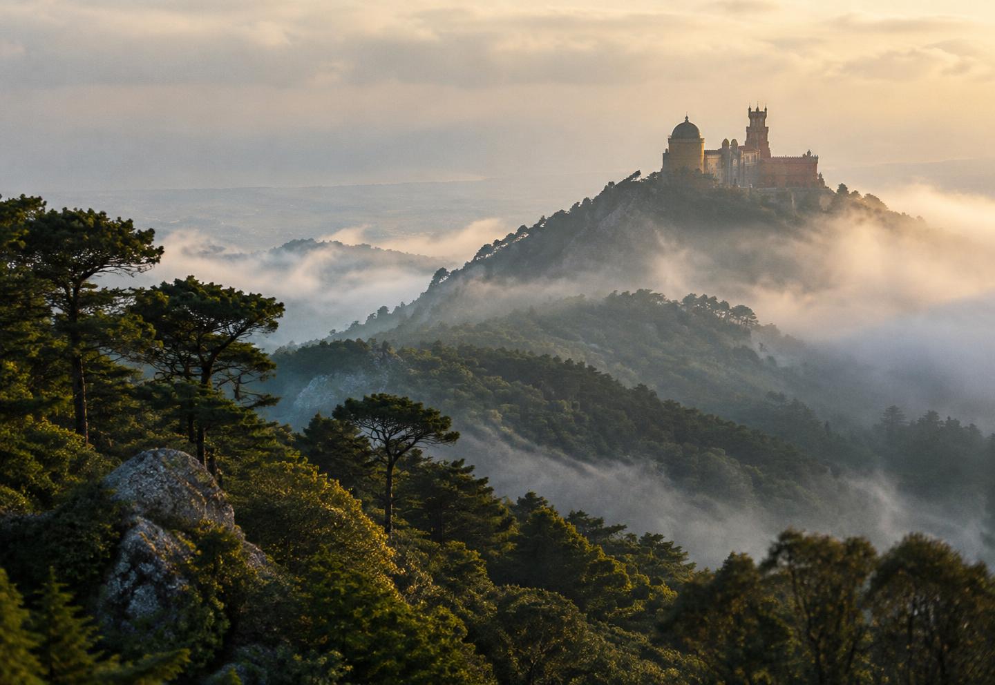 Forested hills with a palace silhouette on a misty peak
